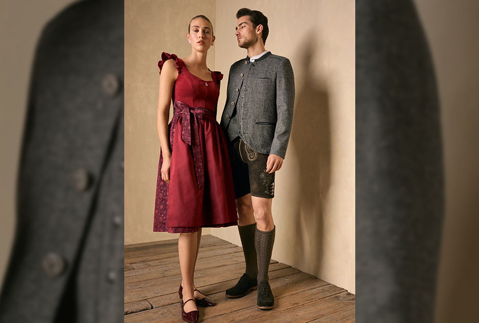 Dame in rotem Dirndl und Herr in dunkelgrauem Trachten-Look